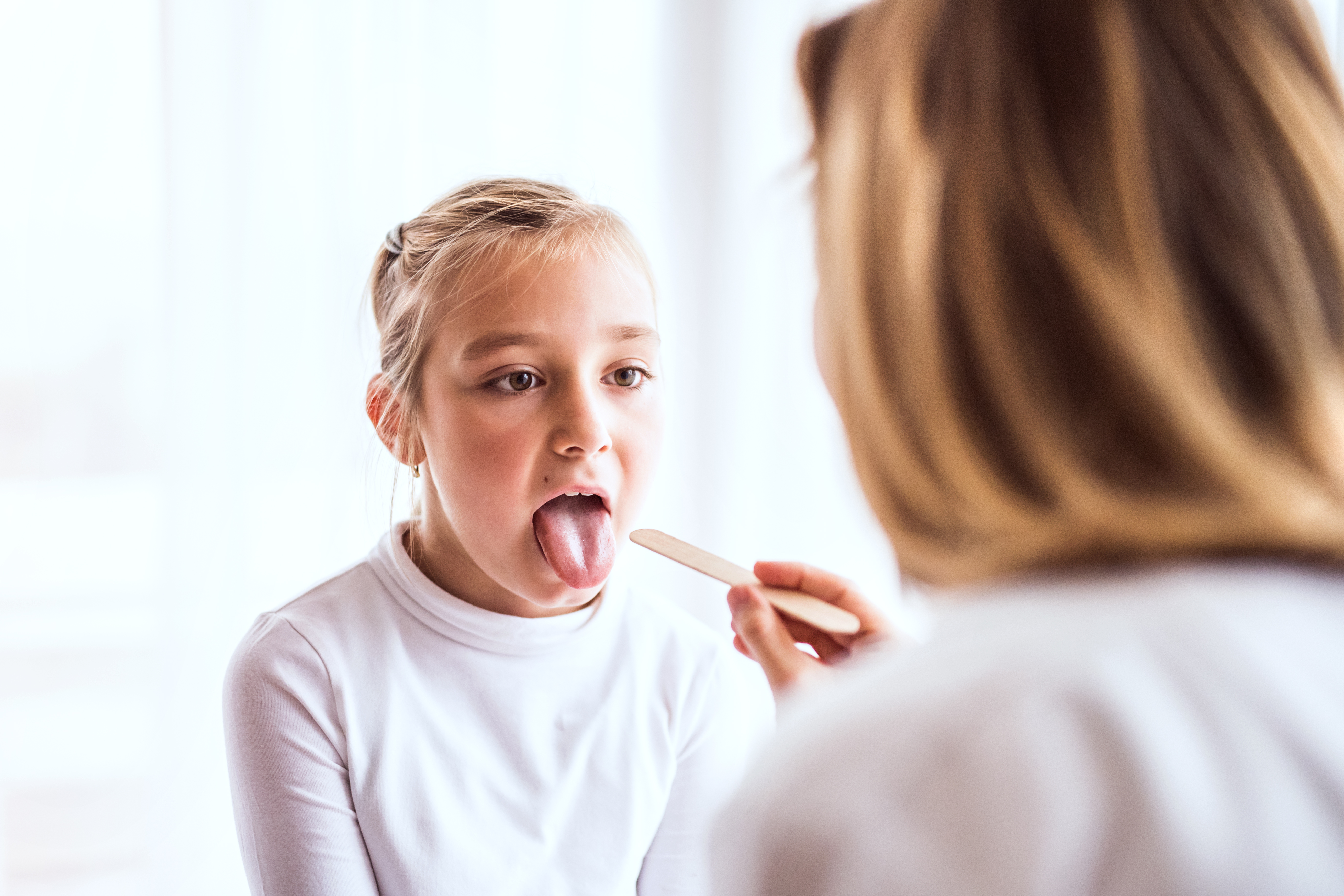 female doctor examining a young girl's tongue and throat
