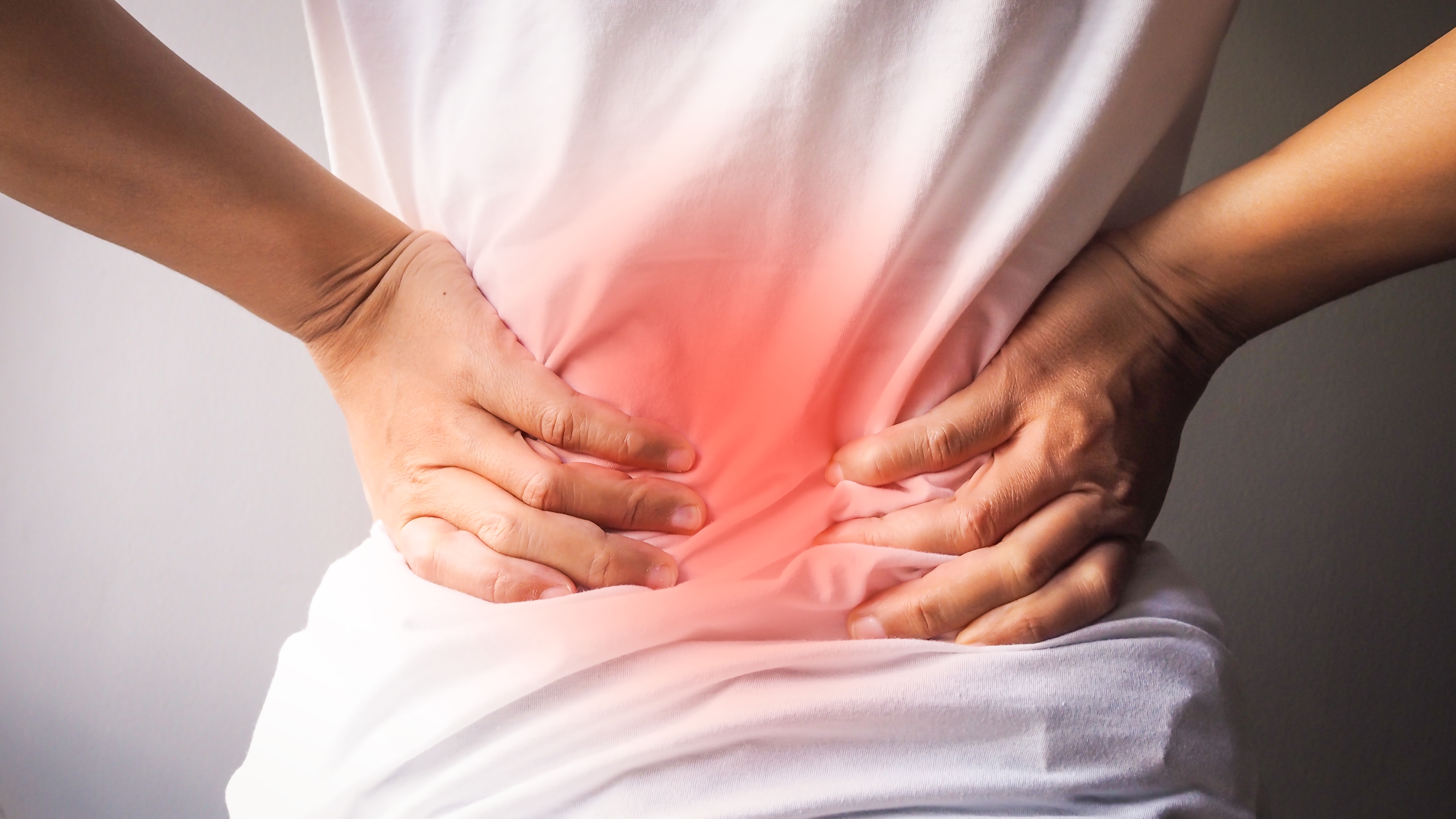 Person clutching their lower back in pain. (Source: Envato)