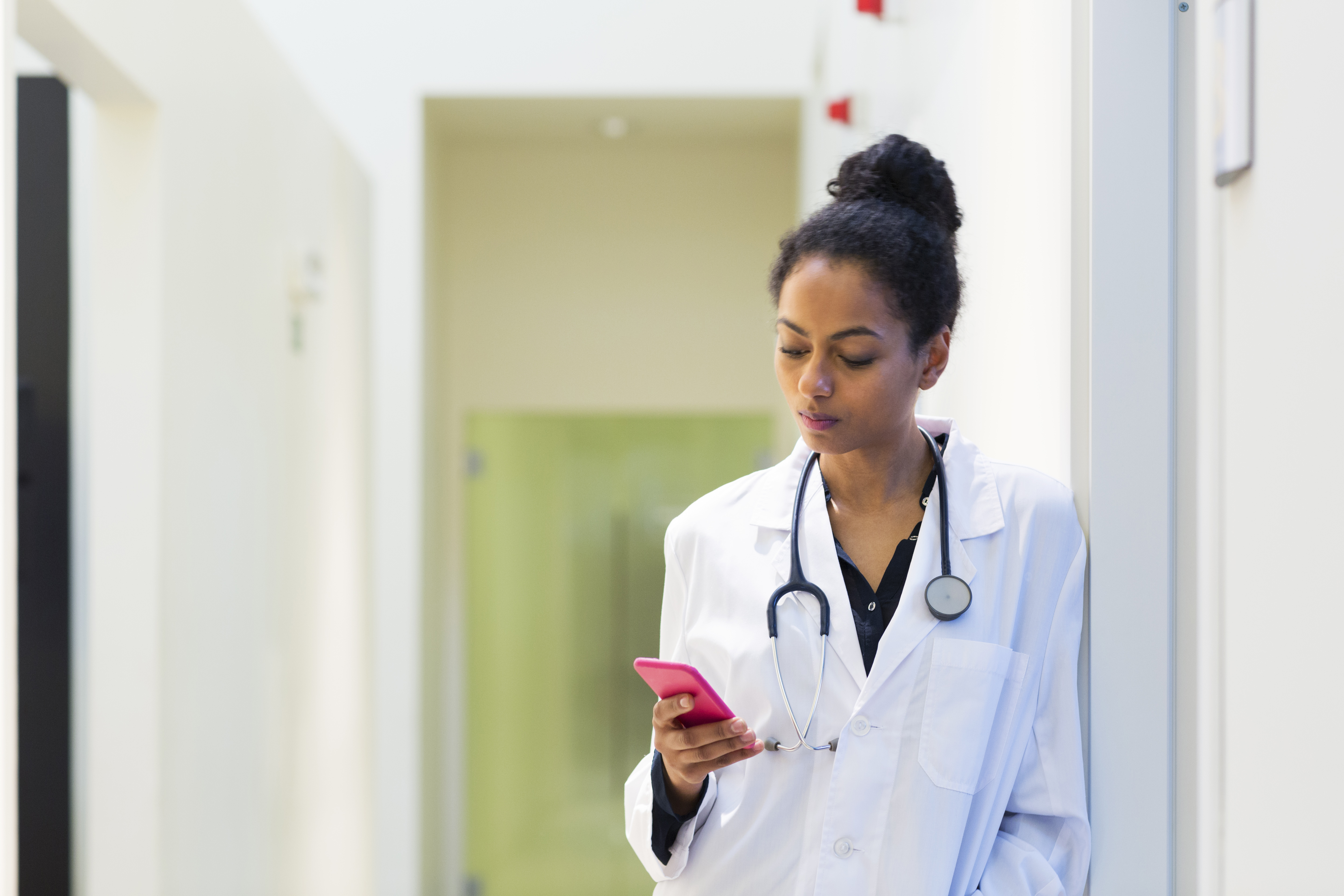 Doctor in hospital looking at mobile phone. (Source: envato)
